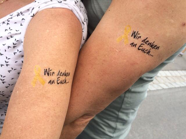 Tattoos Gelbe Schleife mit „Wir denken an Euch“ Tattoos Gelbe Schleife mit „Wir denken an Euch“